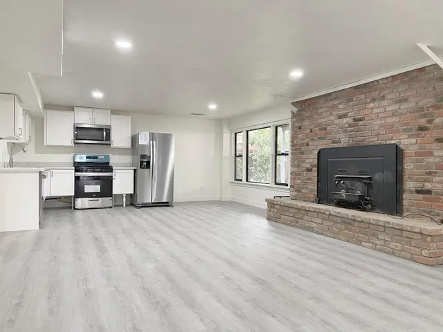an empty room with kitchen and fireplace