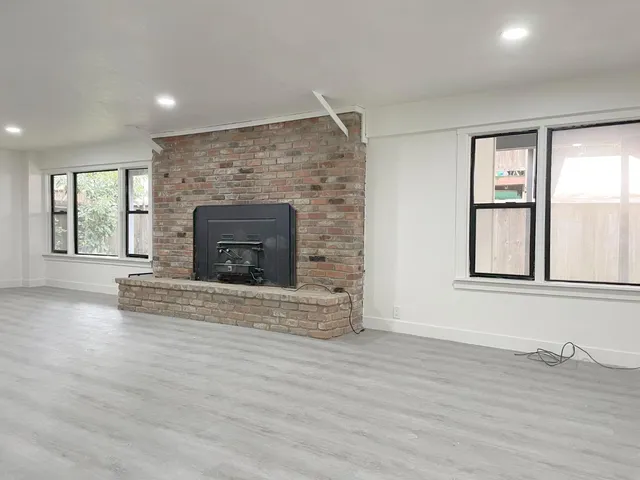 an empty room with wooden floor and fireplace