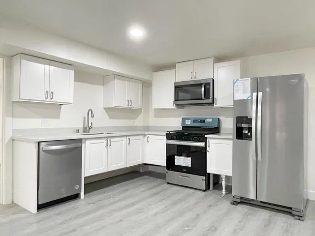 a kitchen with granite countertop a refrigerator stove top oven and sink with wooden floor