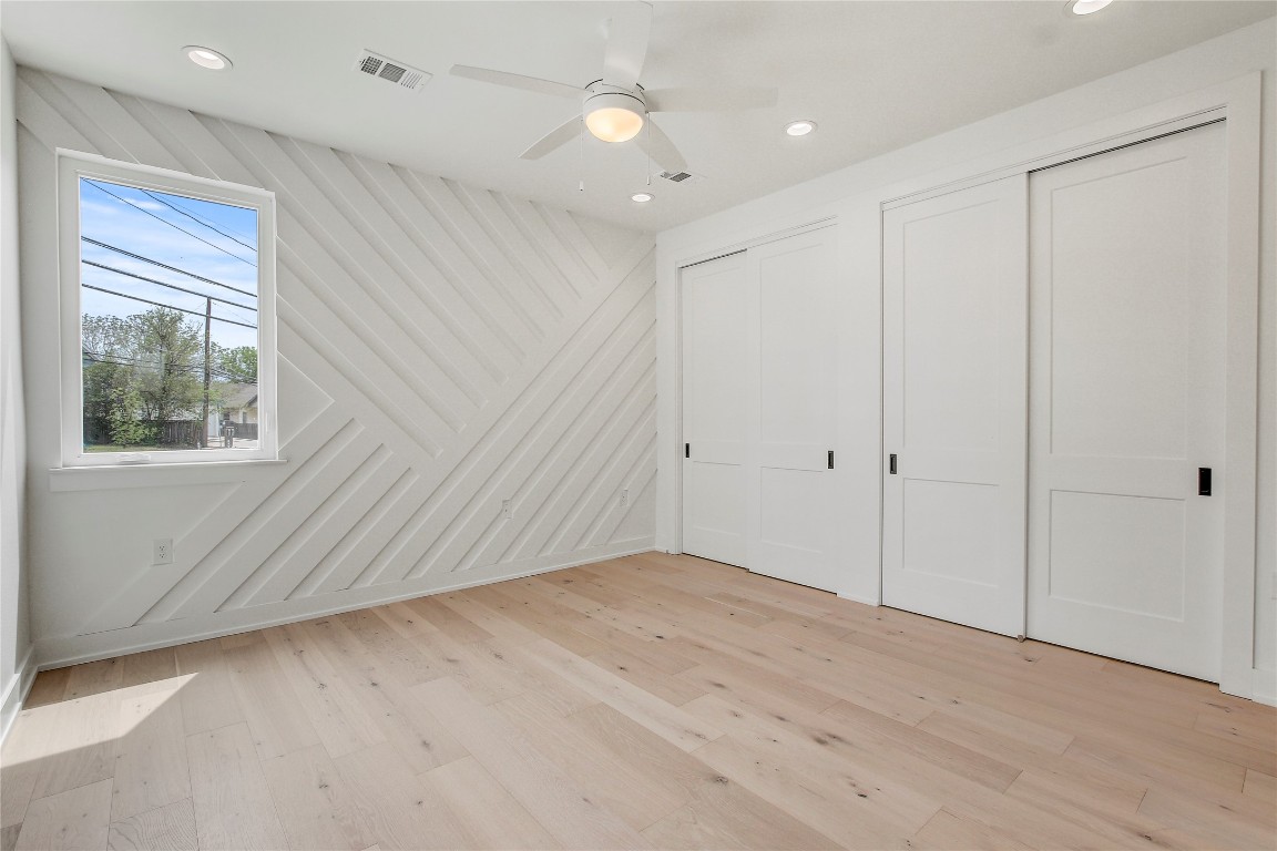 4127 East 12th Street, Unit 6 Austin, TX 78721 - Photo 15 of 17 Unfurnished bedroom featuring two closets, recessed lighting, light wood-style flooring, and ceiling fan