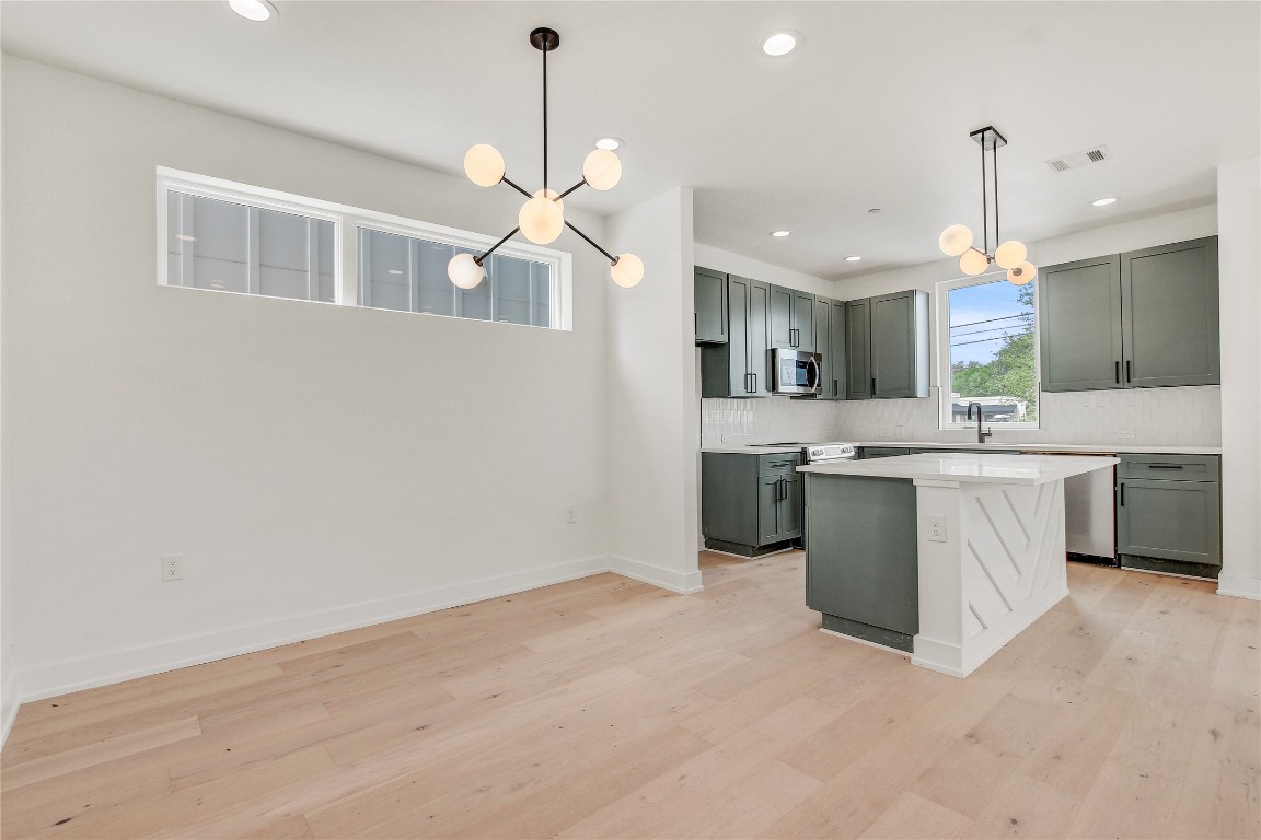 4127 East 12th Street, Unit 6 Austin, TX 78721 - Photo 2 of 17 Kitchen with a chandelier, stainless steel appliances, decorative backsplash, and recessed lighting