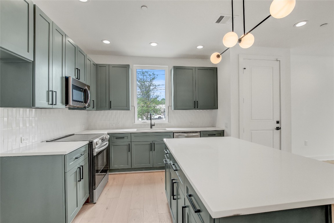 4127 East 12th Street, Unit 6 Austin, TX 78721 - Photo 8 of 17 Kitchen featuring appliances with stainless steel finishes, a sink, recessed lighting, decorative backsplash, and light wood-type flooring