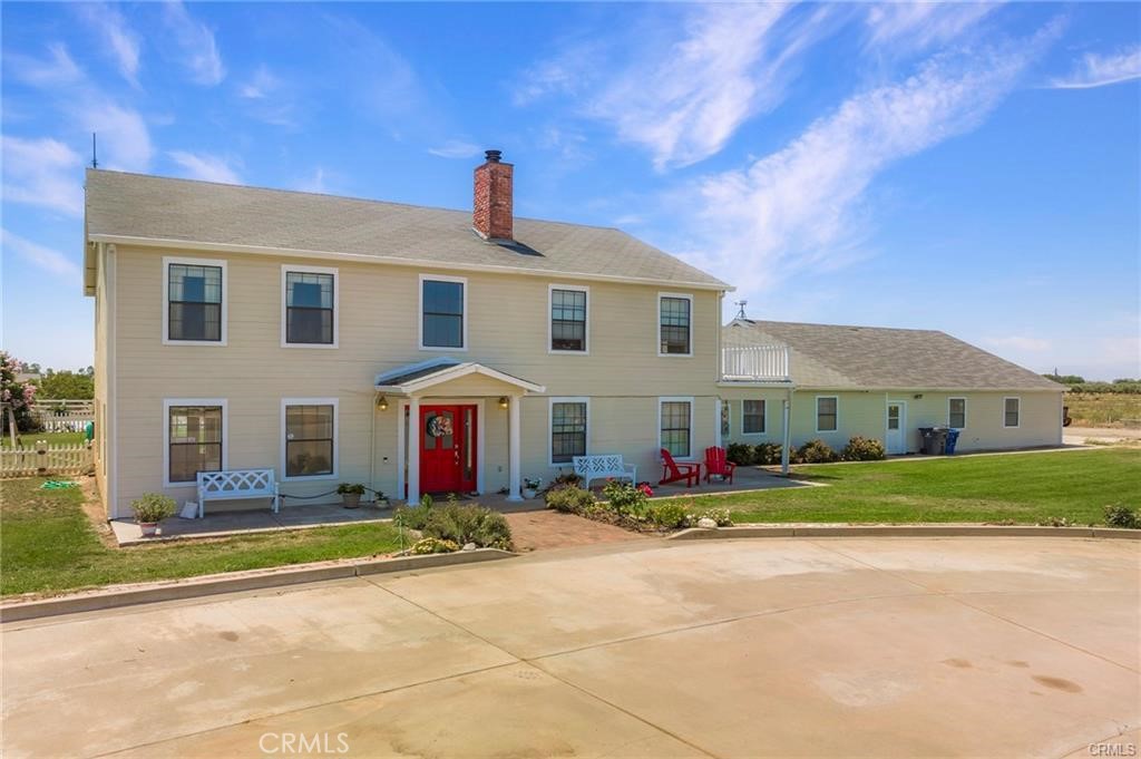 a front view of house with yard and trees in the background