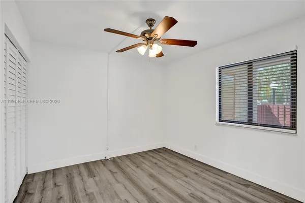 an empty room with wooden floor fan and windows