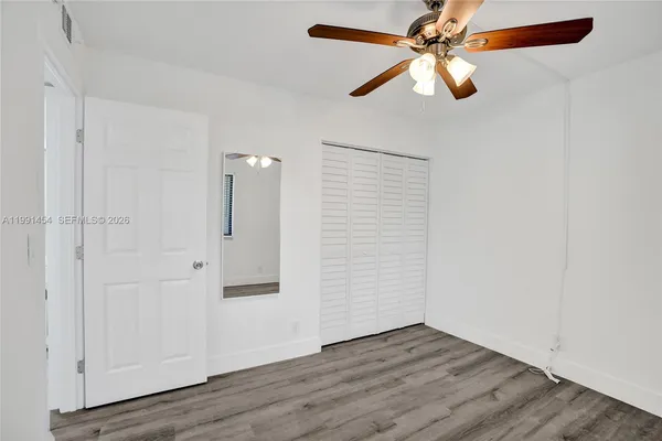 an empty room with wooden floor closet and fan