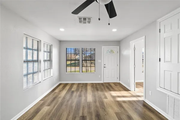 a view of an empty room with wooden floor and a window
