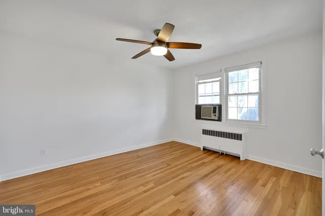 a view of empty room with wooden floor and fan