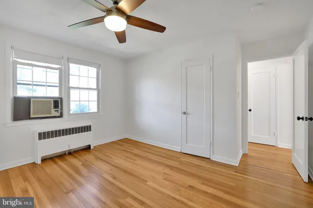 a view of an empty room with window and wooden floor