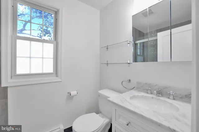 a bathroom with a granite countertop toilet sink and mirror