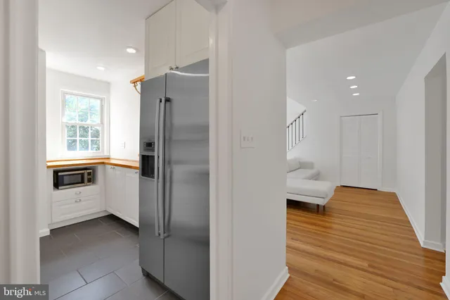a kitchen with a refrigerator and white cabinets