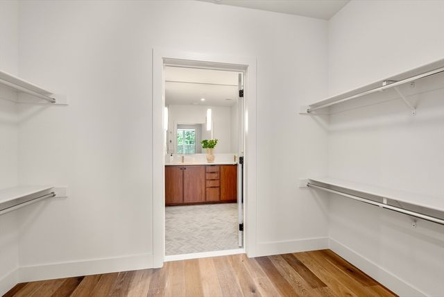 a view of a hallway with wooden floor and a bathroom