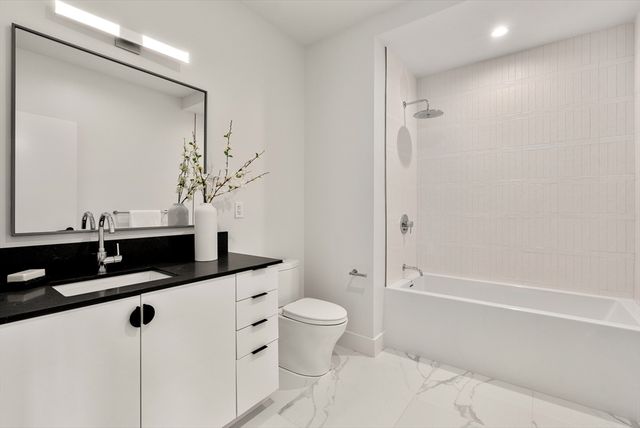 a bathroom with a granite countertop sink a toilet a mirror and shower