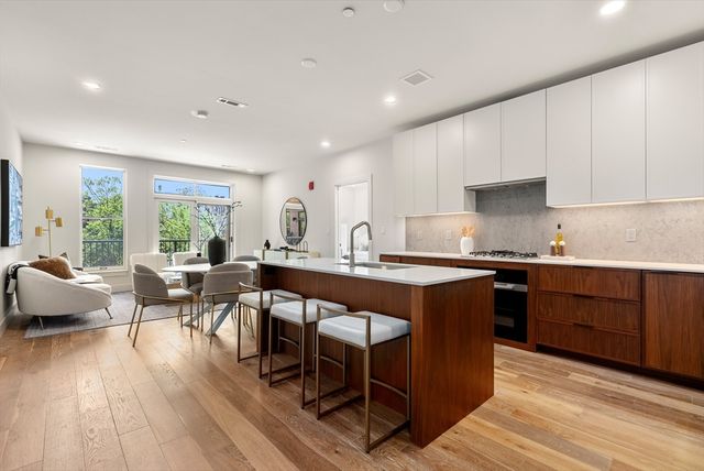 a living room with stainless steel appliances granite countertop a table chairs sink and cabinets