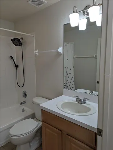 a view of an empty room with wooden floor and a bathroom