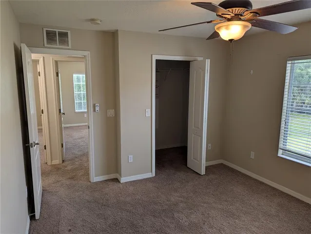 a view of an empty room and a chandelier fan