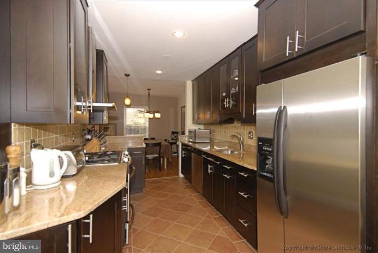 2137 Golf Course Drive Reston, VA 20191 - Photo 1 of 26 a large kitchen with kitchen island a large counter top space a sink stainless steel appliances and cabinets