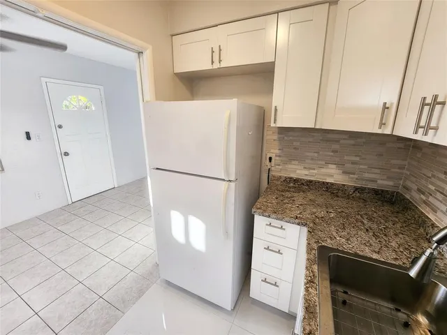a kitchen with white cabinets and a refrigerator