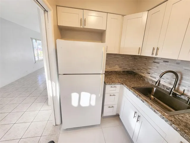 a kitchen with stainless steel appliances granite countertop a sink a refrigerator and a cabinets
