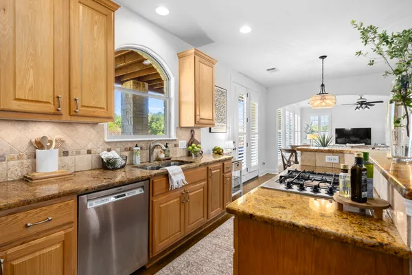 a kitchen with kitchen island granite countertop a sink a counter top space appliances and cabinets