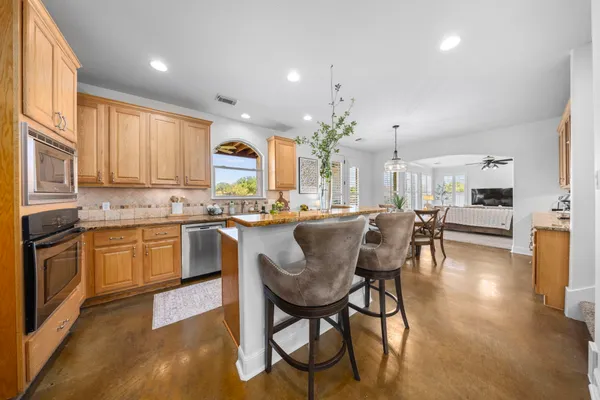 a kitchen with stainless steel appliances granite countertop wooden cabinets a stove a sink and a refrigerator