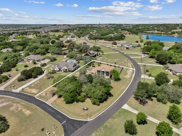 an aerial view of a residential houses with outdoor space and trees