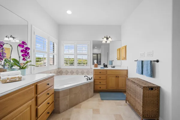 a spacious bathroom with a granite countertop double vanity sink a mirror and a bathtub