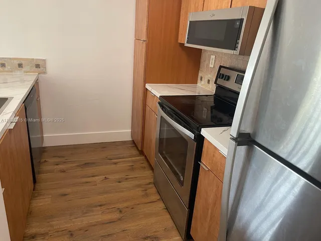 a view of a kitchen with fridge and wooden floor