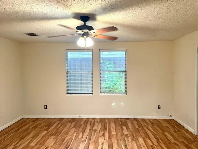 a view of an empty room with a window and a ceiling fan