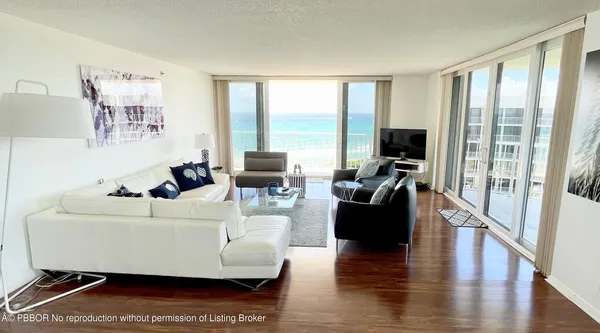 a living room with furniture floor to ceiling window and a flat screen tv