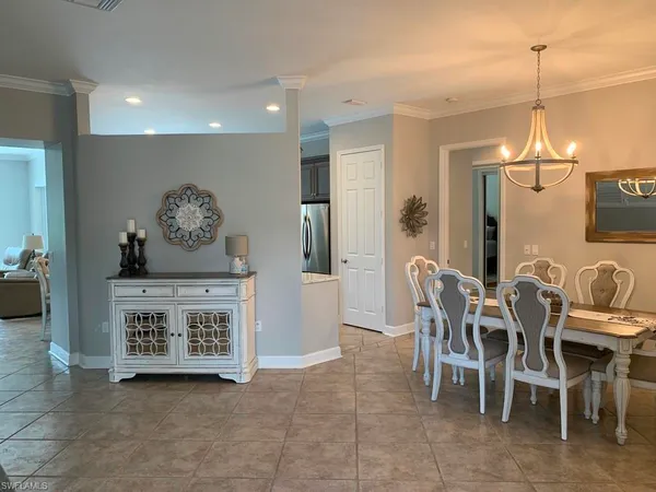a view of a dining room and livingroom with furniture a rug a painting and a chandelier