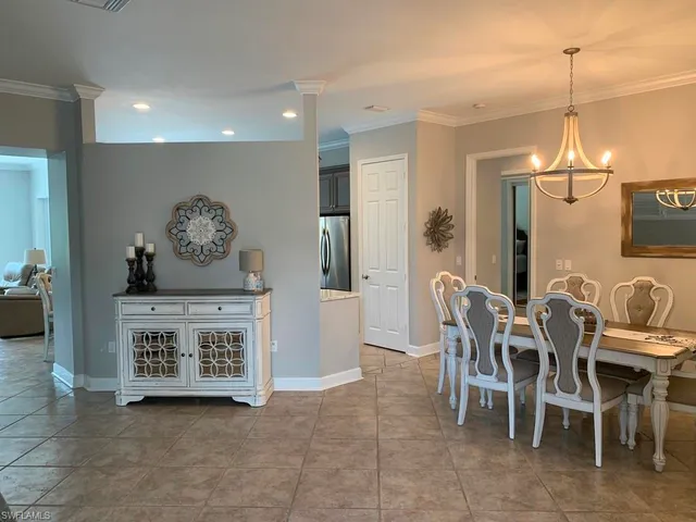 a view of a dining room and livingroom with furniture a rug a painting and a chandelier
