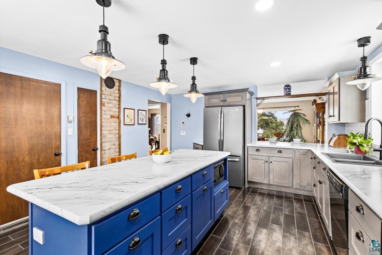 2170 Lester River Road Duluth, MN 55804 - Photo 29 of 66 Two tone kitchen featuring wood finish floors, two tone cabinetry, pendant lighting, stainless steel appliances, and tasteful backsplash