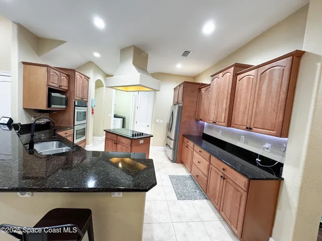 a kitchen with kitchen island granite countertop a sink and a stove top oven