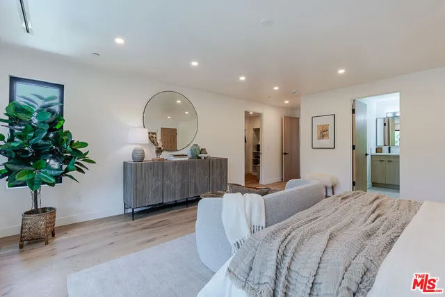 a spacious bedroom with a large bed and a potted plant