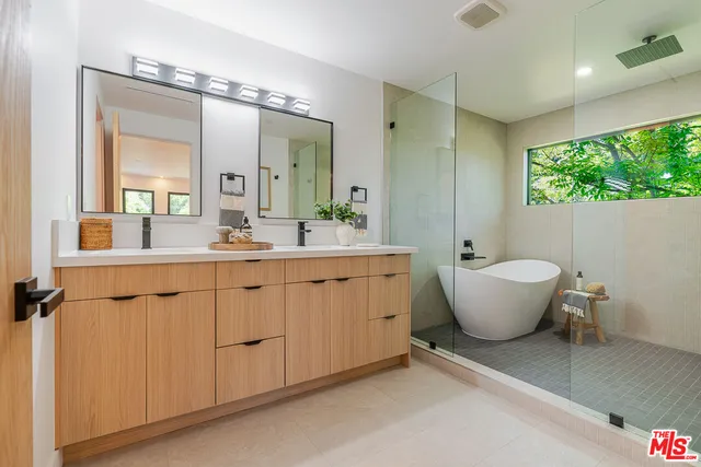 a bathroom with a double vanity sink a mirror and a bathtub