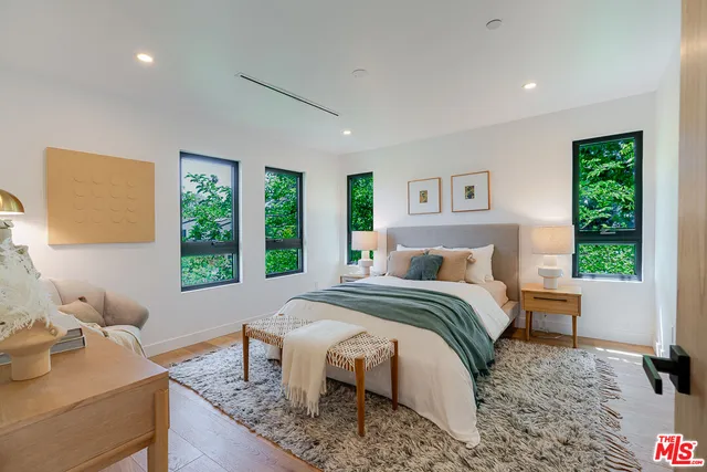 a bed sitting in a spacious bedroom next to a window