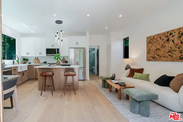 a living room with furniture and a dining table with kitchen appliances