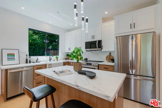 a kitchen with a refrigerator a stove a sink and chairs