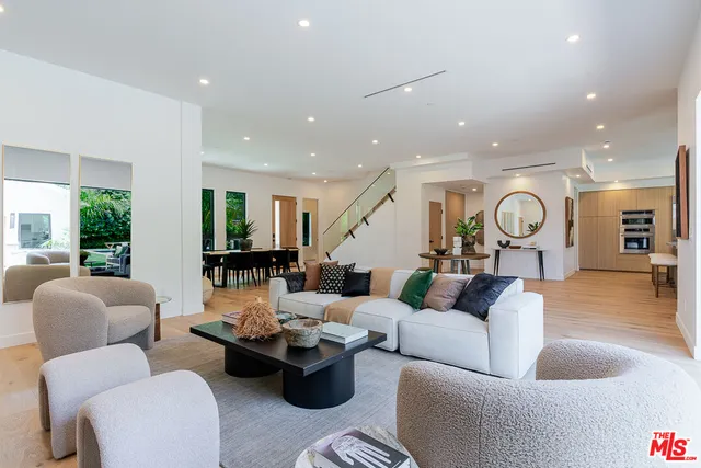 a living room with furniture kitchen view and a large window