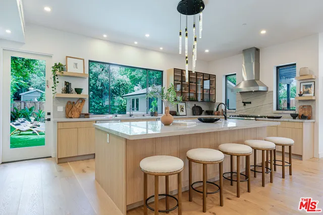 a kitchen with stainless steel appliances granite countertop a table chairs and a refrigerator