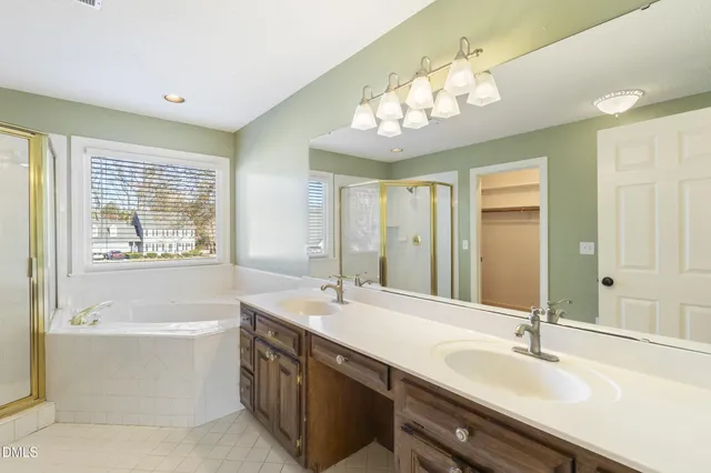 a bathroom with a tub sink shower and two mirror