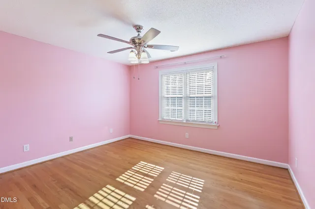 a view of a big room with wooden floor and chandelier fan