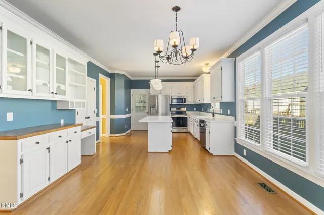 a large kitchen with kitchen island a large counter top space a sink stainless steel appliances and cabinets