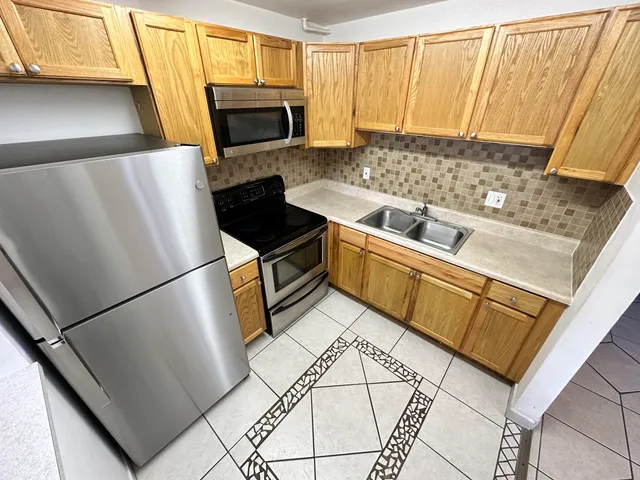 a kitchen with stainless steel appliances granite countertop a refrigerator a stove a microwave oven with a sink and dishwasher