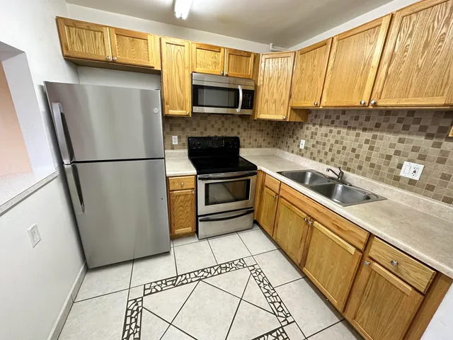 a kitchen with a refrigerator a stove top oven a sink and cabinets