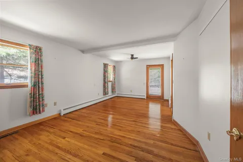 a view of an empty room with wooden floor and a window