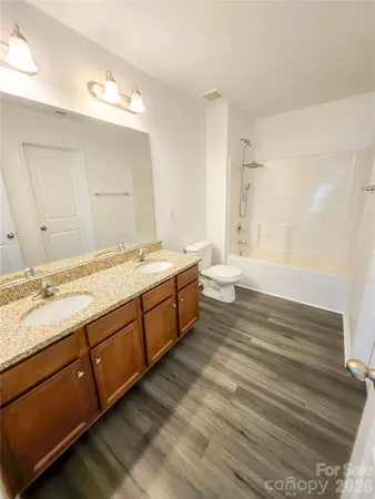 an empty room with wooden floor windows and fan