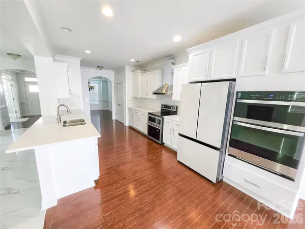 a large white kitchen with sink and refrigerator