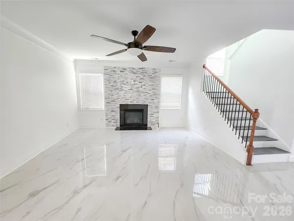 a view of an empty room with wooden floor fireplace and a window