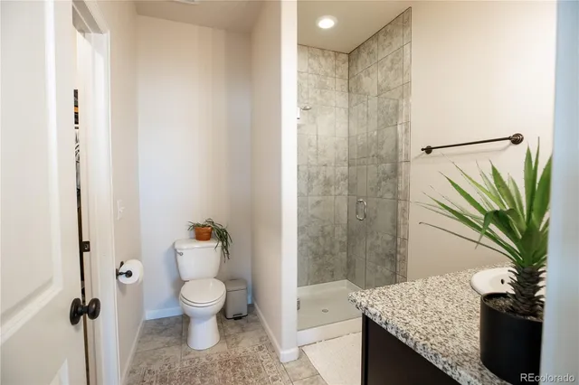 a bathroom with a granite countertop sink a toilet and shower